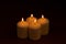 Four whiteÂ candlesÂ flameÂ burningÂ onÂ dark backgroundÂ withÂ copyÂ space forÂ text